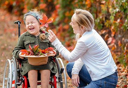 Mutter mit Kind im Rollstuhl, beide lachen